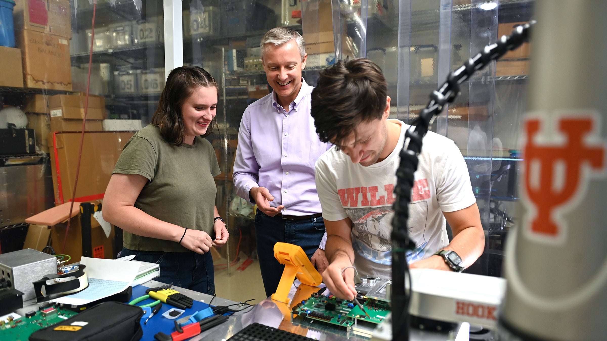 A scientist with two students working in a lab with electronics