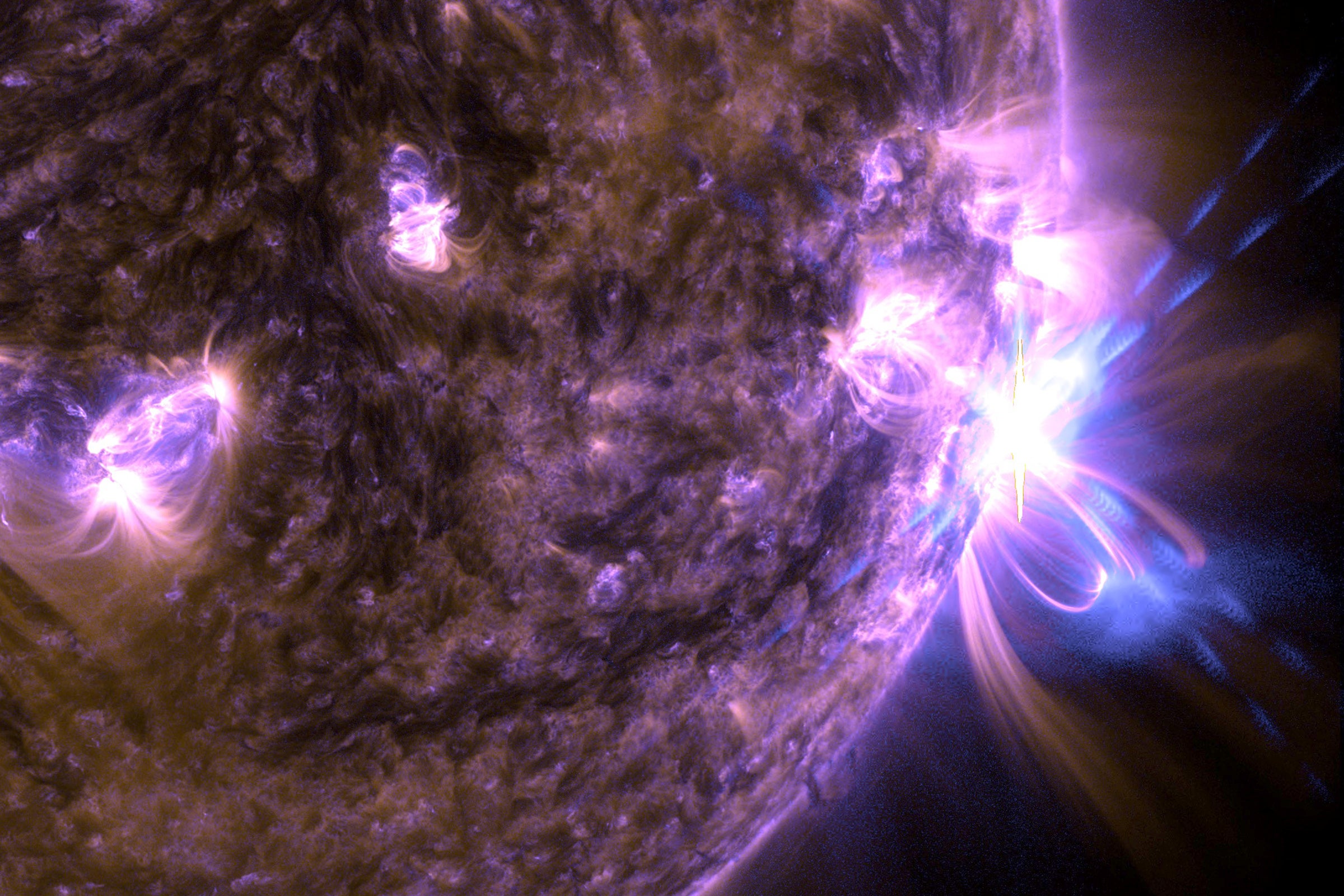 Solar flares on the sun. The image has a purple cast.