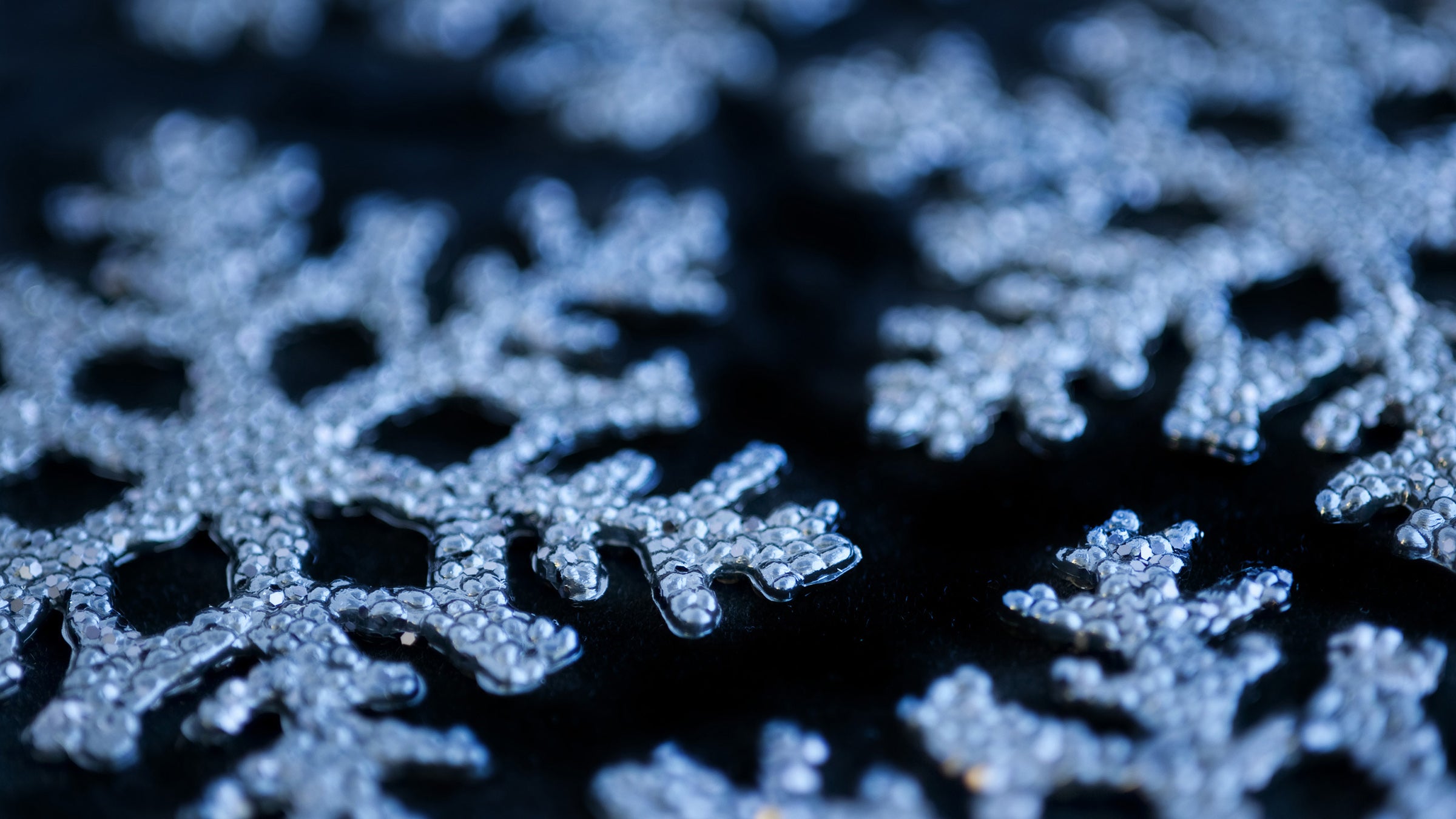 Blueish white snowflakes sparkle on a black background
